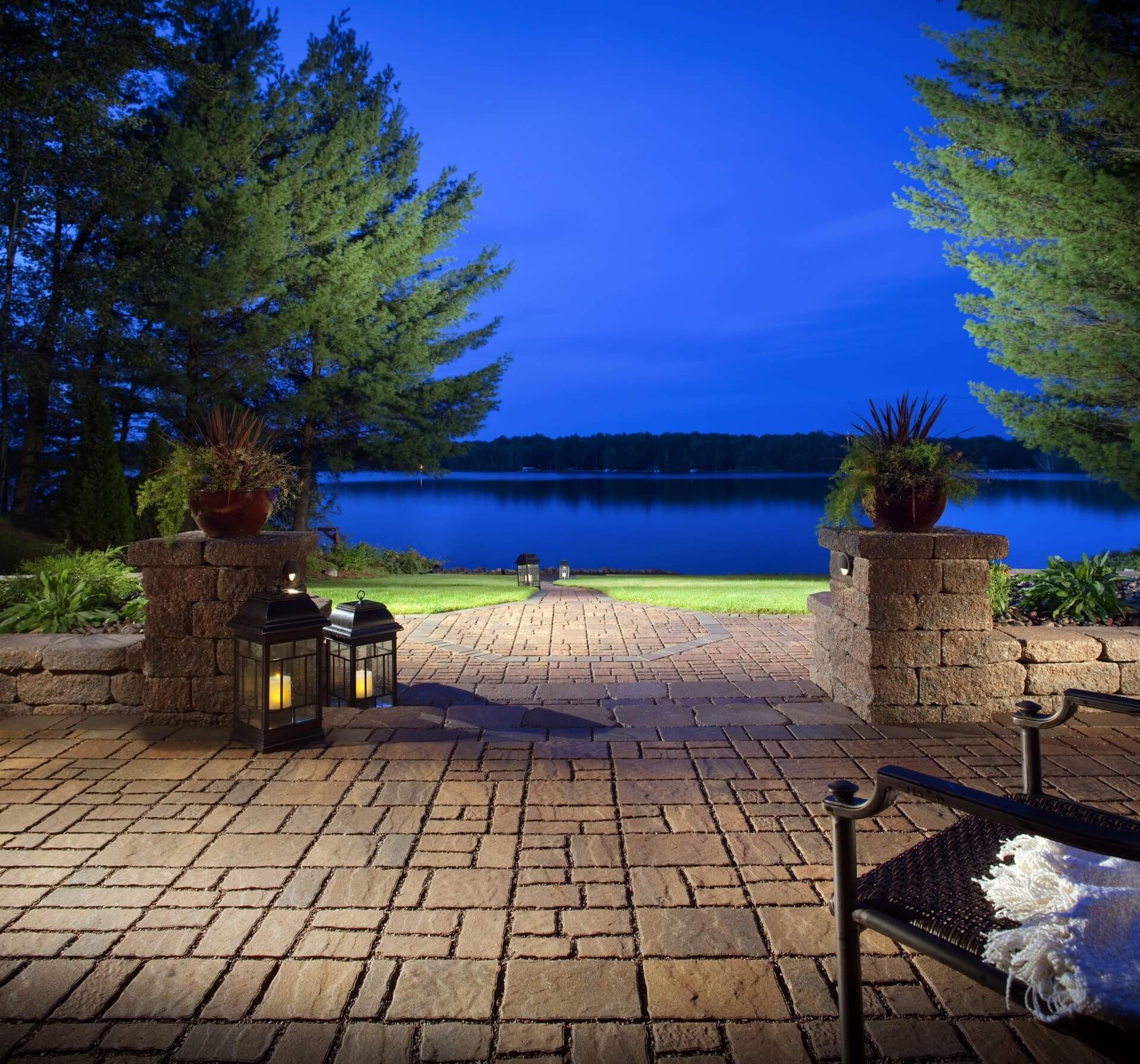 a residential landscape design featuring a stone patio with a lake view