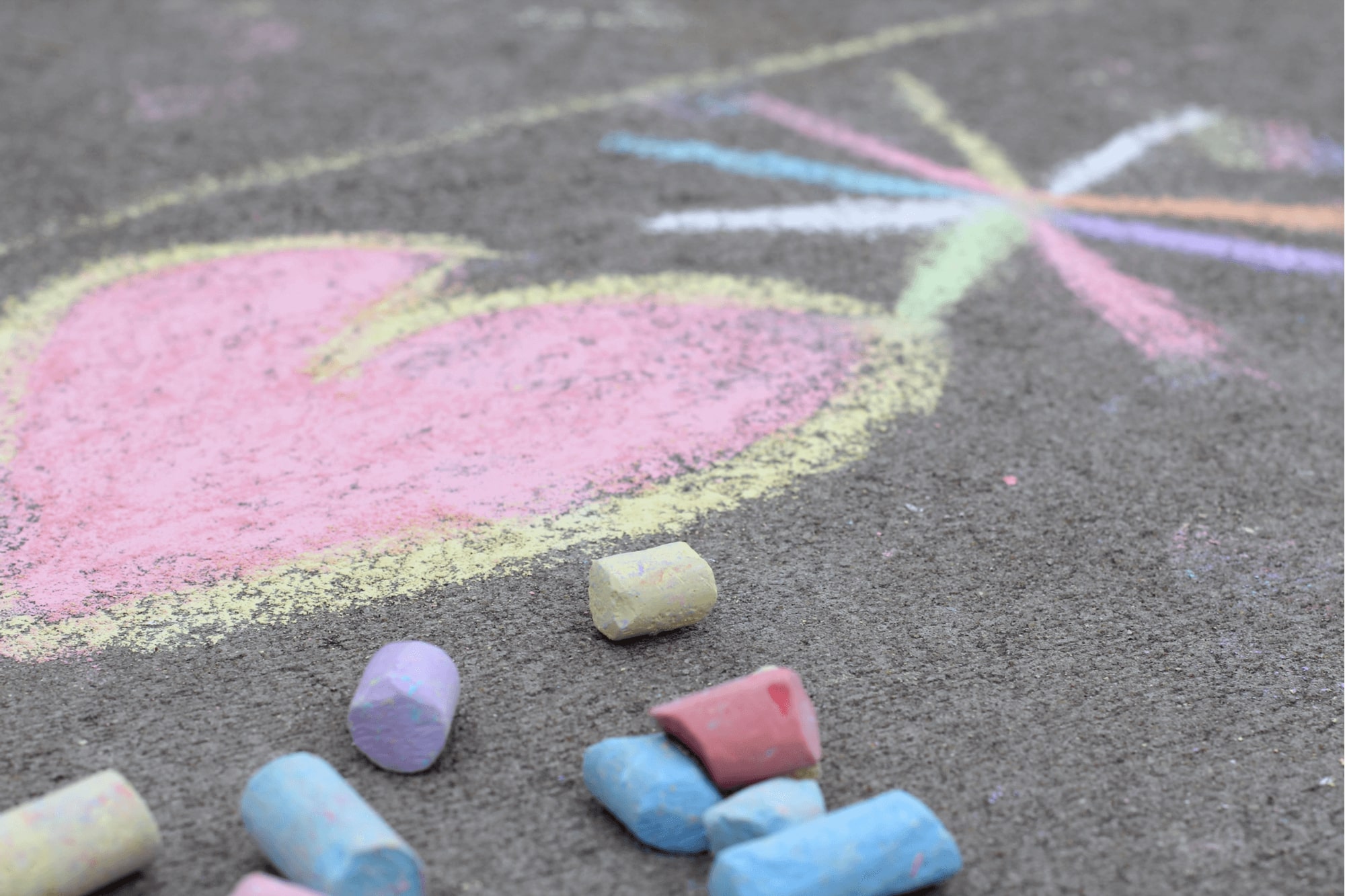 A colorful chalk drawing of a heart and a flower on a concrete sidewalk