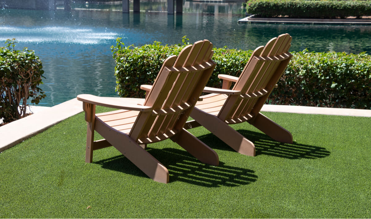 Two Adirondack chairs facing a pond with a fountain