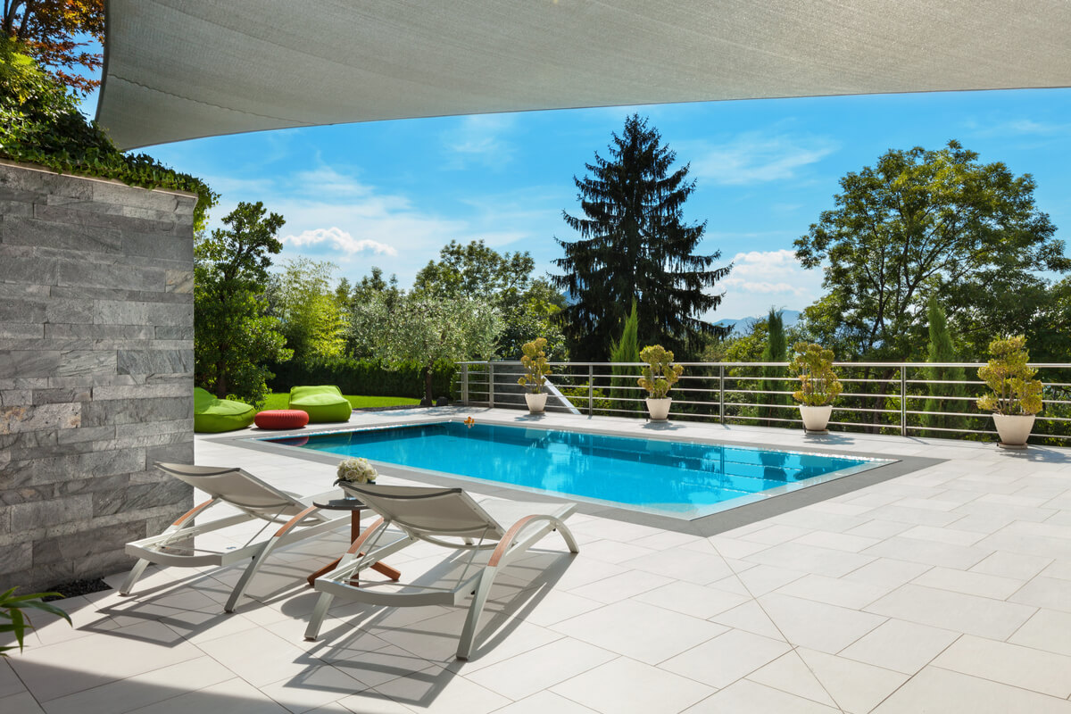 A rectangular swimming pool surrounded by a stone patio