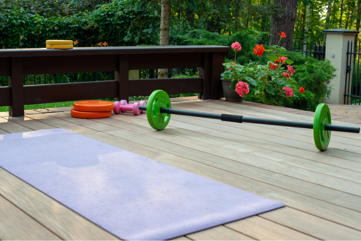 A yoga mat and weights on a wooden deck